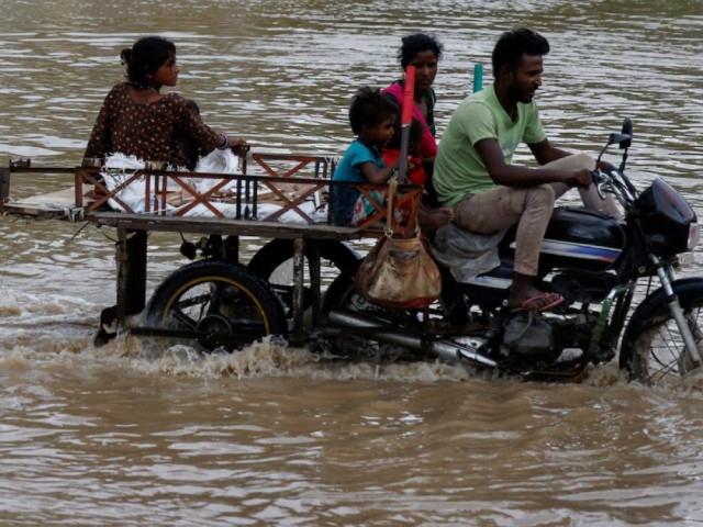 A family crosses a flooded street after heavy rains in Ahmedabad, India, August 28, 2024. PHOTO:REUTERS